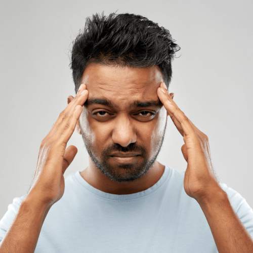 Man experiencing migraine pain, holding his head, illustrating symptoms related to migraine treatment options offered by IV Texas.