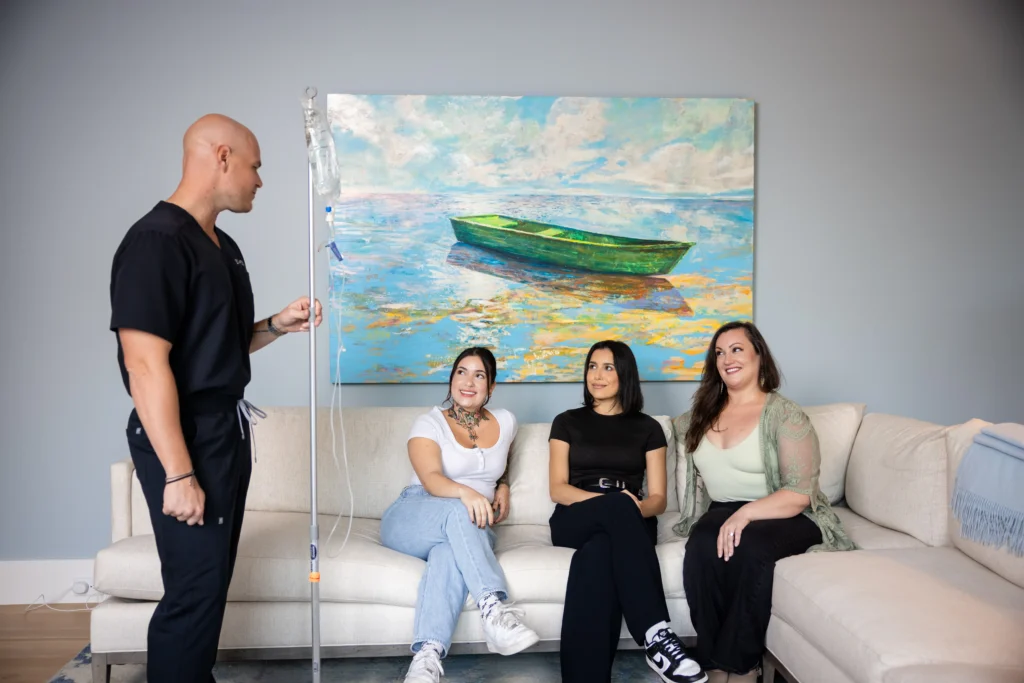 three people sitting while talking to a standing Clinician